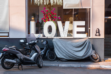 摩托车靠近商店橱窗上的 LOVE 字样。
