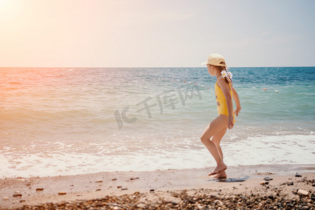 在阳光下奔跑摄影照片_可爱的小女孩在清澈湛蓝的大海的映衬下沿着海边奔跑，在夏日的阳光下欢欣鼓舞。