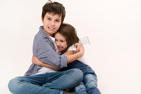 淘气的男孩和可爱的女孩、弟弟和妹妹在白色背景下互相拥抱，有复制空间