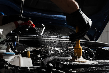 在详细的汽车服务中用喷雾、刷子和洗涤剂清洗汽车发动机。
