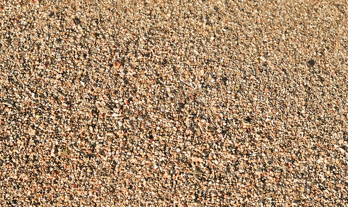 沙滩上的沙子、小鹅卵石和流动的波浪背景。