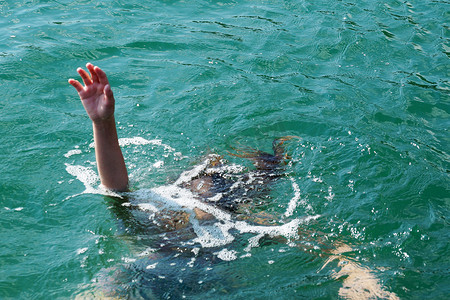 哭泣摄影照片_溺水的女孩将她的手举出水面。