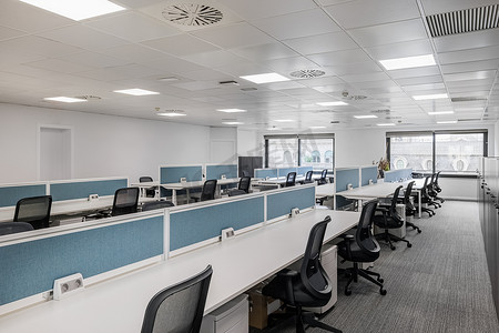灰色调的空办公室，配有长桌和椅子，供管理人员的员工使用，窗户大，自然光线充足。