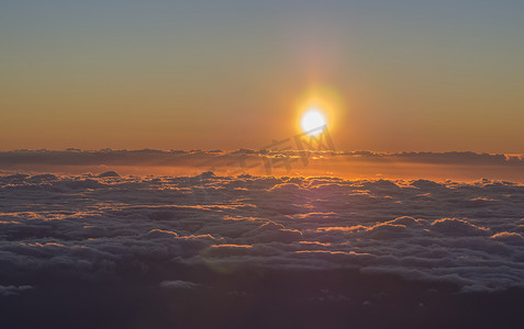 橙红色的日出，太阳升起在蓬松的云层之上，带着阳光和镜头光晕，从 pico del teide tenerife 的顶部拍摄