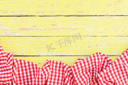 黄色木桌面背景纹理，带有质朴的红色桌布