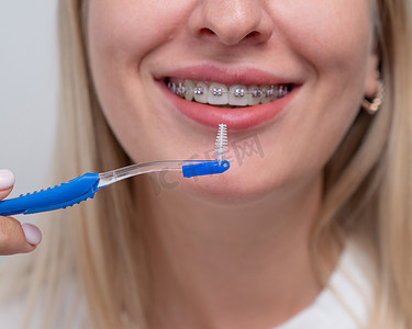 白种女人用刷子清洁她戴着牙套的牙齿。