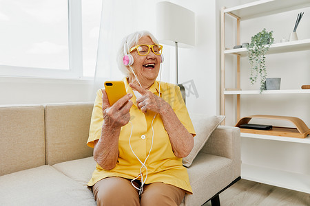 快乐的老年妇女看着电话视频通话微笑、通信技术、明亮的现代室内装饰、生活方式在线通信。
