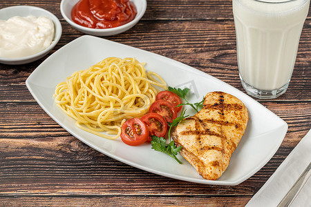 白瓷盘摄影照片_白瓷盘上的意大利面和烤鸡，木桌上放着酪乳和酱汁