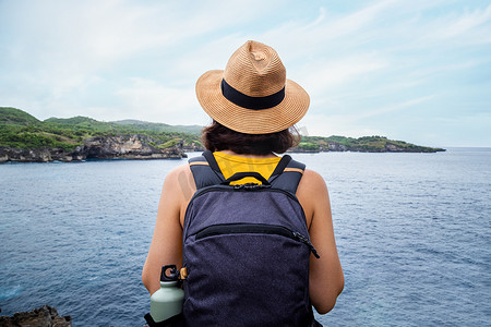 巴厘岛努沙佩尼达度假时看海的旅行者的背影。背着背包的女性在大自然中享受自由。