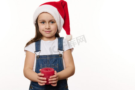 快乐的白人小孩，戴着圣诞帽的可爱女婴，拿着圣诞蜡烛，可爱地笑着看着镜头