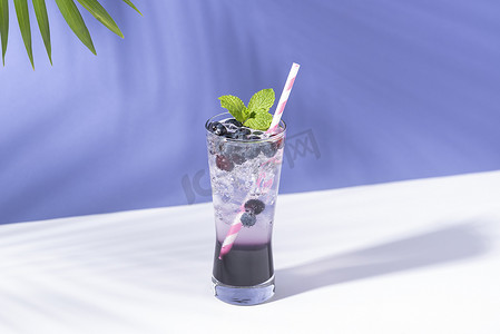 冷清摄影照片_冷清爽的蓝莓潘趣鸡尾酒，紫色背景薄荷。