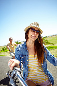 骑自行车、旅行和情侣度假的女人，暑假在蓝天背景下享受户外骑行的乐趣。
