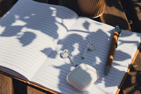 用带无线耳机的纸质笔记本带走工艺回收纸杯中的咖啡。