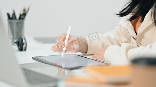 女经济学家手持手写笔在数字平板电脑上书写、在办公桌上处理统计数据的裁剪镜头
