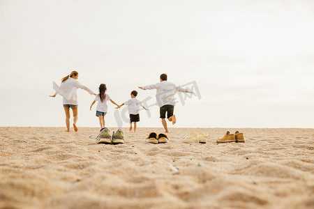 有孩子的家庭父母的后视图享受手拉手一起跑到海滩的乐趣