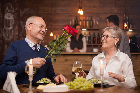 六十多岁的丈夫在餐厅给妻子送玫瑰
