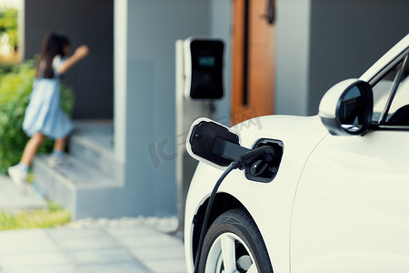 聚焦 EV 汽车在家庭充电站充电，背景模糊的女孩。