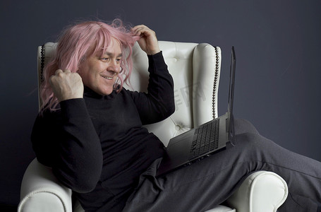 一个戴着粉色假发的男人坐在椅子上，通过视频链接进行交流。