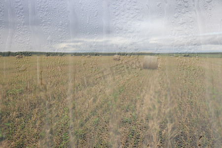 雨后玻璃摄影照片_金秋雨后的农田，湿玻璃后面的天空中有云。
