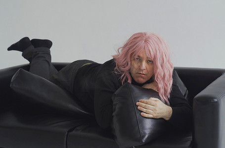 假发摄影照片_一个戴着粉红色假发的醉汉躺在沙发上，正在醒来。
