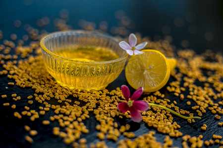 著名的天然头皮屑在玻璃碗中的木制表面上的方法由胡芦巴种子粉与柠檬汁充分混合而成。表面上有生柠檬和胡芦巴种子。
