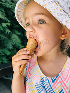 拿冰棍摄影照片_小女孩用手拿着华夫饼锥吃冰淇淋
