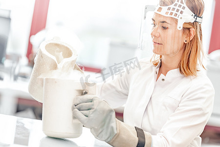 液氮摄影照片_实验室里的液氮研究是由一位戴着防护玻璃面罩的年轻女科学家进行的