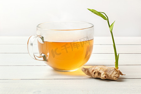 白公猪桌上放着绿芽的干姜根，旁边放着一杯刚泡好的茶。