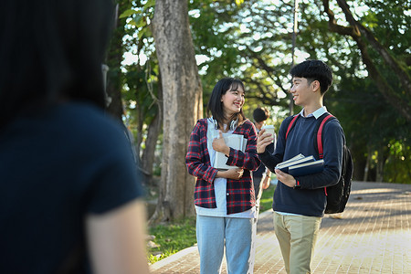 两个快乐的大学生走在校园里，去上课，互相交谈。