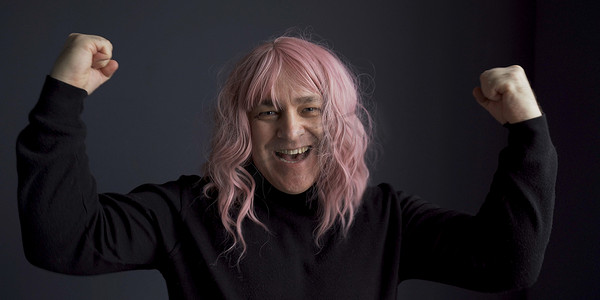 戴着粉红色假发的积极男人为成功而高兴。