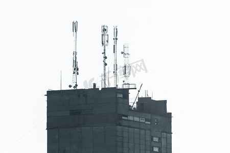 混凝土建筑轮廓屋顶上的蜂窝通信无线移动信号塔和互联网通信网络