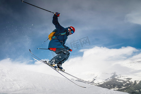 男人滑雪摄影照片_男性滑雪者从山上跳下创造雪羽，冬季极限运动，下坡滑雪