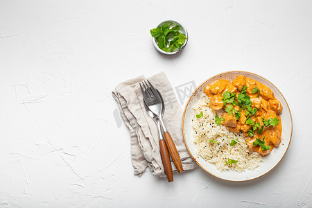 传统的印度菜咖喱鸡配印度香米和新鲜香菜，放在白色混凝土桌子背景的质朴白盘子上。