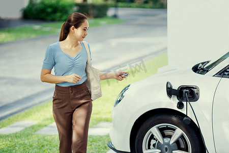 进步女性在家里的充电站给她的 EV 汽车充电。