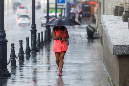 雨中街道摄影照片_一个男人在雨中走在雨伞下，脸离开了镜头