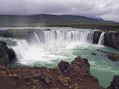 冰岛瀑布摄影照片_有灰色云彩的著名冰岛瀑布 Godafoss