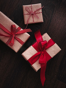 传统经典摄影照片_圣诞礼物和传统节日礼物，木制背景的经典圣诞礼盒，用红丝带工艺纸包裹的礼物，复古乡村风格的季节性假期