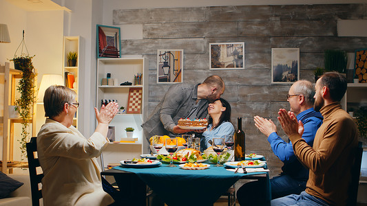 舒适家人摄影照片_女人和与朋友和家人共进晚餐，吃蛋糕惊喜