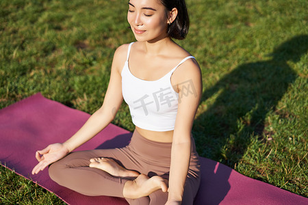 做背景摄影照片_微笑的亚洲女性冥想、在新鲜空气中做瑜伽、在橡胶垫上放松、在公园锻炼、呼吸空气、冷静