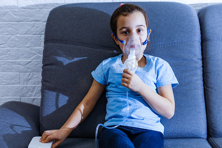 白人小女孩戴着特殊的面具呼吸，这有助于阻止哮喘发作或缓解呼吸道疾病的症状。