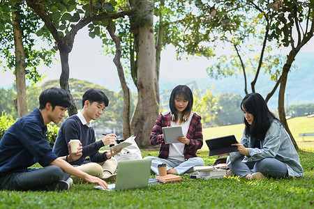 年轻的亚洲大学生在美好的一天坐在校园草坪上进行小组项目和交流
