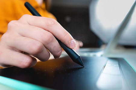 随便的人，自由职业者用手写笔在数字平板电脑屏幕上书写，在办公桌上的笔记本电脑上工作。