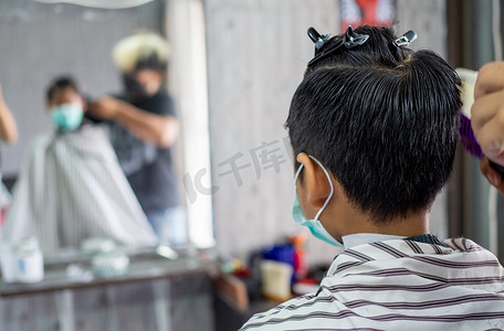 戴着面罩的十几岁男孩正在理发店理发。