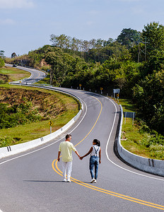 一对夫妇在南泰国山区一条弯曲的路上行走，3 号乡村公路