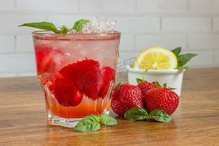 一种清新的夏日饮品，在木质背景下加入冰块、草莓和柠檬。