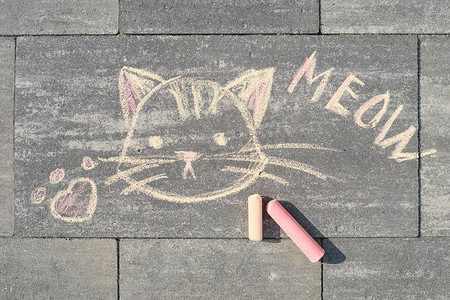 用蜡笔写在灰色人行道上的喵喵文字和猫图片