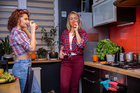 壁柜摄影照片_厨房里的两个女孩用高脚杯喝果汁