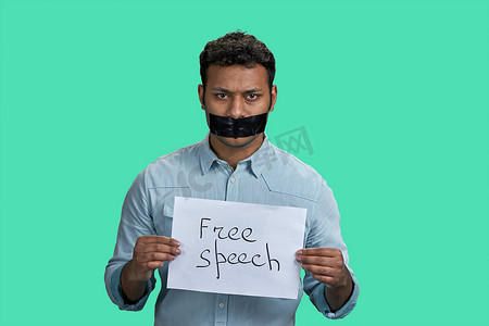言论自由摄影照片_印度男子用胶带封住嘴巴，拿着写有言论自由题词的纸。