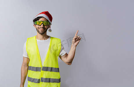 戴着圣诞帽的建筑工人用手指指着促销活动。