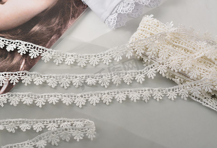 本色白色凸花带，浅色背景上的美丽丝绸蕾丝面料。